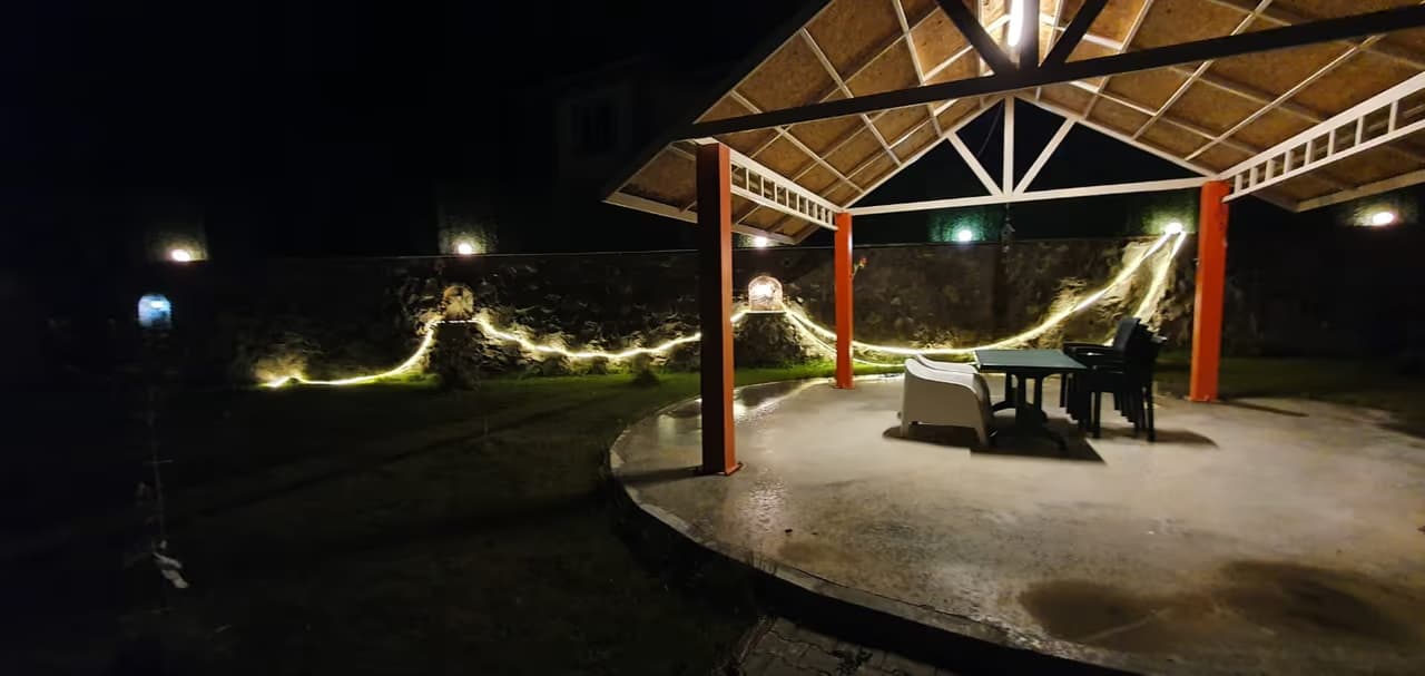 Taş duvar boyunca LED şerit, kamelya altı armatürler ve dökme beton oturma platformu.